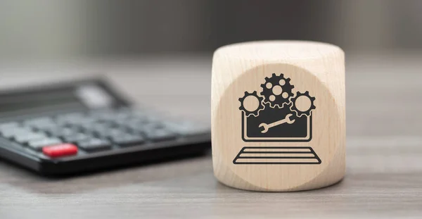 Wooden block with symbol of system maintenance concept and calculator on background