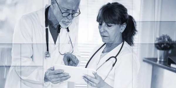 Двоє Зрілих Лікарів Обговорюють Медичний Звіт Цифровому Планшеті Геометричний Візерунок — стокове фото