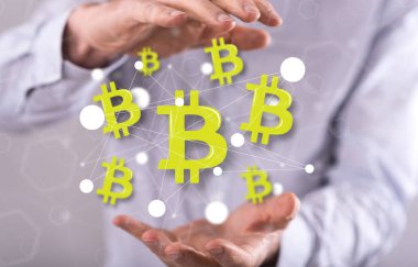 Arka planda bir adamın elleri arasında Bitcoin kavramı