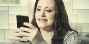 Evde cep telefonu kullanan çekici genç bir kadın, geometrik desenli.