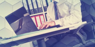 İşadamı masasında oturuyor ve dizüstü bilgisayar, geometrik desen üzerinde çalışıyor.