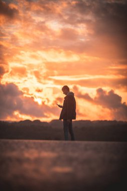 man on the background of the orange sky stands with his back