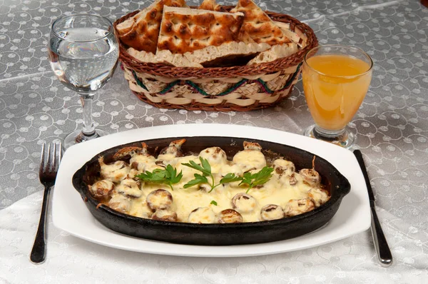 Oven baked cheddar mushrooms. The mushroom on the clay plate is on the dining table.