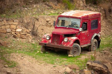 Eski, terk edilmiş bir kırmızı retro araba bir dağ köyünün kenarında..