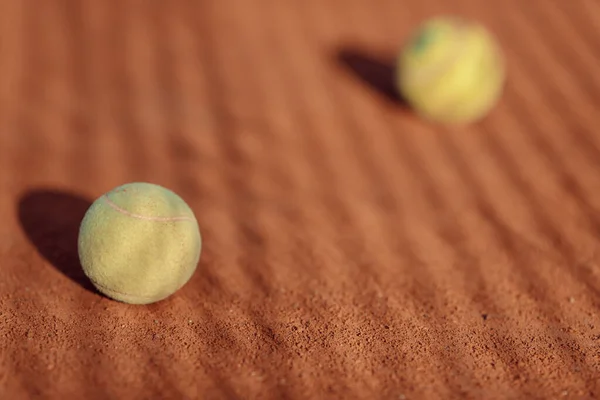 tennis ball on a clay court sun