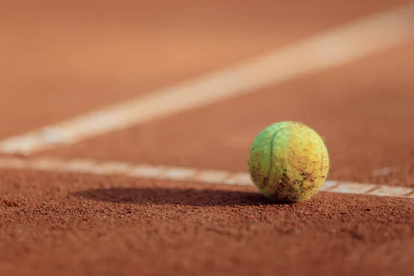 tennis ball on a clay court sun