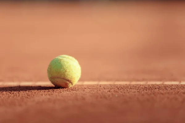 tennis ball on a clay court sun