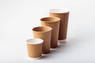 Kahve için dört boş kağıt bardak. Beyaz arka planda farklı boyutlarda kahve fincanları.