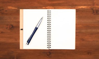 Boş sayfalar ve ahşap bir masa üzerinde bir kalem olan not defterini aç..