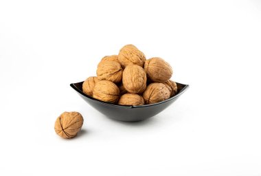 Beyaz arka planda siyah tabakta cevizler.