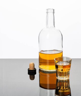 Beyaz arka planda mantarlı bir bardak ve bir şişe alkol..