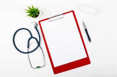 Üzerinde steteskop, hap, çiçek ve kalem bulunan tıbbi pano. Üst görünüm..