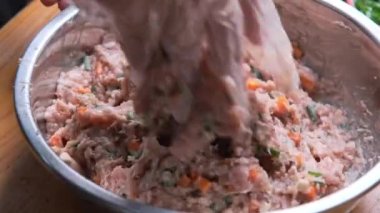 Kadın, terbiye edilmiş domuz pirzolası, doğranmış havuç, soğan ve küçük dilimlenmiş Shiitake mantarlarını karıştırmak için tek kullanımlık plastik eldiven içinde..