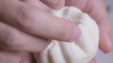 Kadın aşçı elleri hamuru terbiye edilmiş domuz pirzolasıyla şekillendiriyor ve üzerine tuzlanmış yumurta sarısı ekliyor. Doldurulmuş çörek yapma süreci..