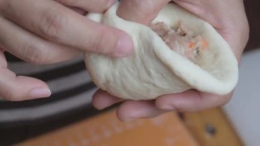 Kadın aşçı elleri hamuru şekillendiriyor. İçinde terbiye edilmiş domuz pirzolası var. Doldurulmuş çörek yapma süreci..
