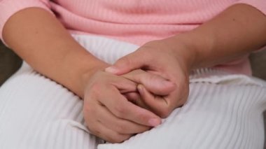 Kanepede oturan genç kadın başparmak ağrısı (De Quervain sendromu) hisseder ve evde eline masaj yapar. El yaralanması veya kronik artrit iltihabı. Sağlık ve tıbbi kavramlar.
