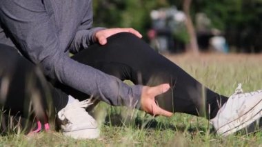 Athlete woman massage leg with cramping in the calf muscles during running training outdoors. Closeup of female runner touching leg in muscle pain. Muscle sports injury.