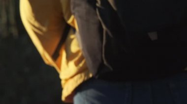 Sonbaharda tropikal bir ormanda yürüyüş yapan sarı ceketli genç bir kadın. Sağlıklı ve aktif bir Asyalı kadın gezgin ormanda bir sırt çantasıyla yürüyor..