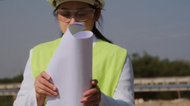 Baraj inşaatında çalışan Asyalı kadın mühendis elinde planlar tutuyor. Kadın mimar yeni bir proje planlıyor..
