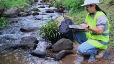 Çevre mühendisleri su kalitesini doğal su kaynaklarında inceler ve verileri dizüstü bilgisayarlara kaydederler. Kadın bilim adamı ve çevre sorunları. Dünya çevre günü kavramı.