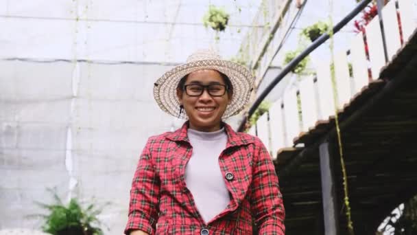 温室内の花の植物の上に立つ笑顔の庭師の女性 フラワーガーデンで働く若い女性起業家 小規模事業主の立ち上げ — ストック動画