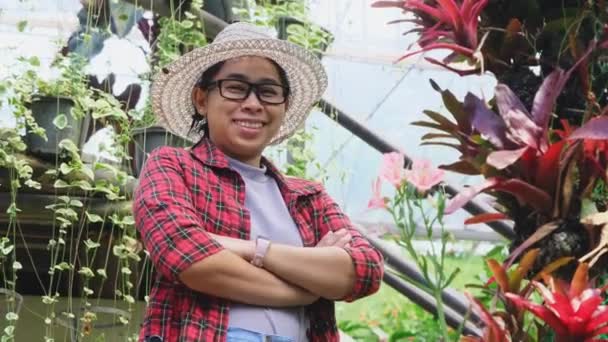 一个微笑的园艺师女人抱着胳膊站在温室里的花卉上的画像 在花园工作的年轻女企业家 小企业主的创业 — 图库视频影像