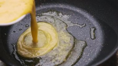 Ev yapımı omletler için kahvaltı hazırlayan eller, tavaya yumurta ve ahşap spatula karıştırıyor. Kahvaltı hazırlıyorum. Sağlıklı gıda konsepti.