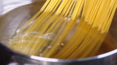 Makarnayı, mutfak ocağındaki çelik tavada kaynar suda yakın plan yap. Evde yemek pişirmek. Ev yapımı Carbonara spagettisi.