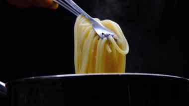 Yakın plan, maşayla haşlanmış makarna kaldırma. Evde yemek pişirmek. Ev yapımı Carbonara spagettisi hazırlığı.