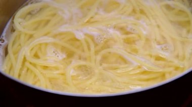 Çelik tencerede kaynar su içinde spagetti makarna yakın çekim. Evde yemek pişirmek. Ev yapımı Carbonara spagettisi hazırlığı.