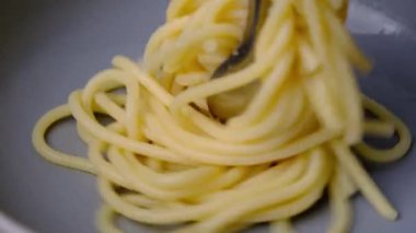 Makarnayı bir tabaktan carbonara sosuyla alan çatala yakın çekim. Çatallı sıcak spagetti. İtalyan Mutfağı ve Ev Yemekleri Konsepti