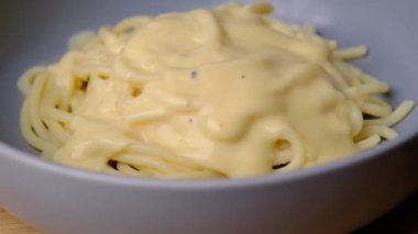 Makarnayı bir tabaktan carbonara sosuyla alan çatala yakın çekim. Çatallı sıcak spagetti. İtalyan Mutfağı ve Ev Yemekleri Konsepti