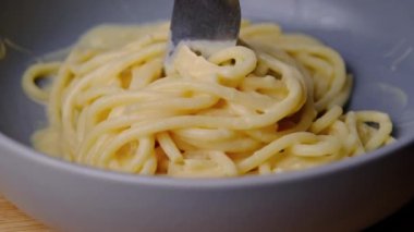 Makarnayı bir tabaktan carbonara sosuyla alan çatala yakın çekim. Çatallı sıcak spagetti. İtalyan Mutfağı ve Ev Yemekleri Konsepti