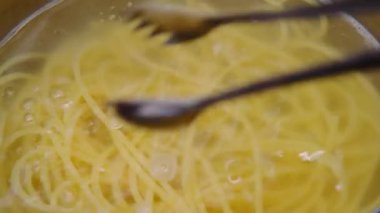 Yakın plan, maşayla haşlanmış makarna kaldırma. Evde yemek pişirmek. Ev yapımı Carbonara spagettisi hazırlığı.