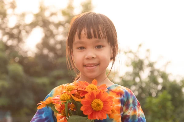 一个阳光明媚的夏夜 一个戴着春花的可爱小女孩的画像 微笑的女孩手里拿着一束鲜橙花 — 图库照片