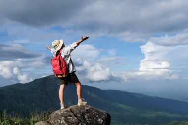 Mutlu kadın yürüyüşçü, kollarını dağ vadisine uzatmış mavi gökyüzü ile bir kayanın üzerinde duruyor. Mutlu kadın dağlarda doğanın tadını çıkarıyor ve gökyüzünü elleriyle seyrediyor. Özgürlük kavramı
