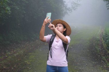 Yağmur ormanlarında cep telefonu üzerinde çalışan bir kadın çevreci. Biyologlar akıllı telefonlara veri yükler ve inceler. Turist telefon kamerasıyla fotoğraf çekiyor ve doğanın tadını çıkarıyor..