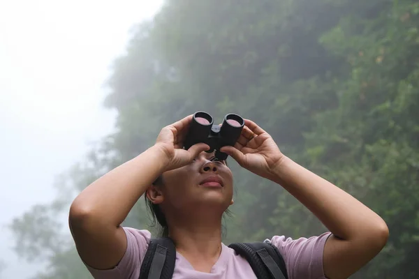 女环保主义者在热带雨林中使用双筒望远镜 女探险家用双筒望远镜旅行 带着快乐的笑容 游客们通过双筒望远镜观看丛林中的野鸟 — 图库照片