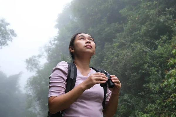 女环保主义者在热带雨林中使用双筒望远镜 女探险家用双筒望远镜旅行 带着快乐的笑容 游客们通过双筒望远镜观看丛林中的野鸟 — 图库照片