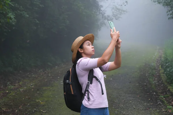 在热带雨林里用手机工作的女性环保主义者 生物学家检查数据并将其输入智能手机 游客们用她的手机相机拍照 享受大自然 — 图库照片