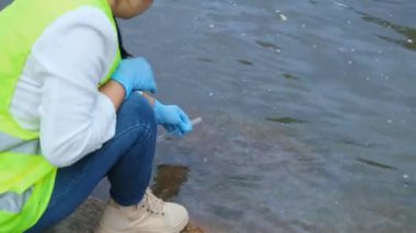 Eldivendeki kadın çevreci eller enfeksiyonları araştırmak ve test etmek için nehirden su örnekleri topluyor. Su ve ekoloji kavramı