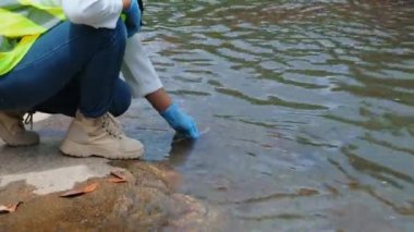 Eldivendeki kadın çevreci eller enfeksiyonları araştırmak ve test etmek için nehirden su örnekleri topluyor. Su ve ekoloji kavramı