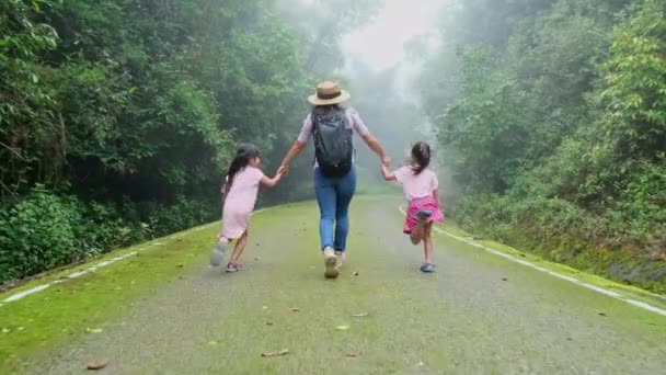 バックパッカーの家族は 熱帯雨林の苔むした道を歩いています 森の中で手をつないで歩くアジアの観光客の幸せな家族 旅行と自由の概念 — ストック動画