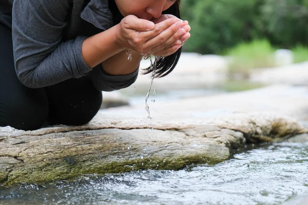 女性が手で川のきれいな水をすくっている きれいな山の川に手を取り水を撒く女 — ストック写真