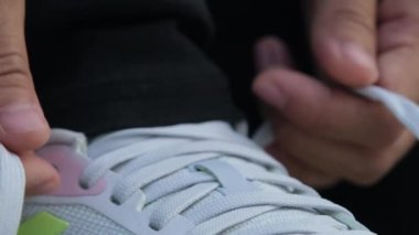 Close up of young woman tying shoelaces on sneakers. Woman tying a shoelace and preparing for fitness.
