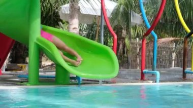 Aquapark 'ta su kaydırağındaki çocuk. Küçük kız yüzme havuzunda eğleniyor. Yaz tatili.