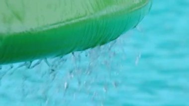 Close-up shot of water dripping from a mushroom-shaped fountain at a water park.