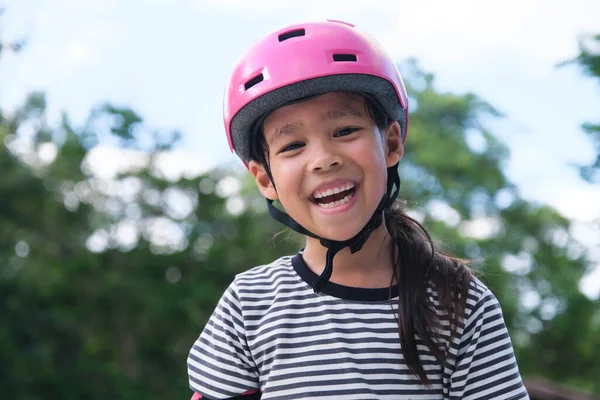 一个戴着头盔笑着的小女孩学习滑冰的肖像 可爱的小女孩在公园练习轮滑 鼓励儿童参加户外活动 — 图库照片