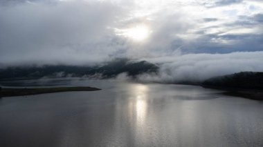 Aerial view from drone, beautiful view of morning mist covering forests and mountains with calm rivers. (Lam Taphen Reservoir), Kanchanaburi Province, Thailand