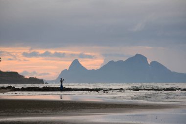Silhouette of a young photographer taking pictures during an amazing sunrise on the beach.